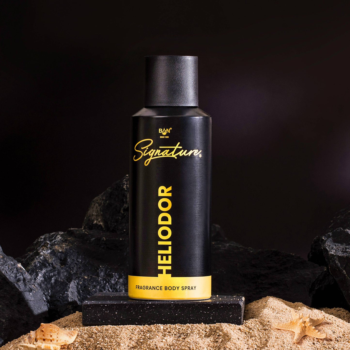 Heliodor fragrance body spray bottle on a black background with rocks and sand.